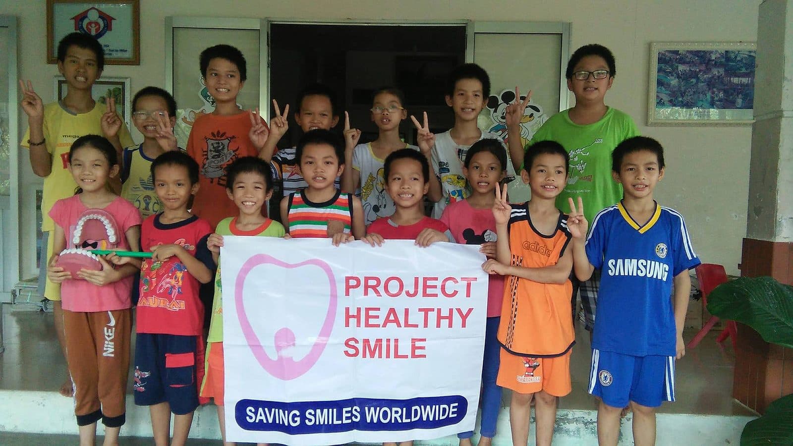 Project Healthy Smile - Kids holding a Project Healthy Smile banner